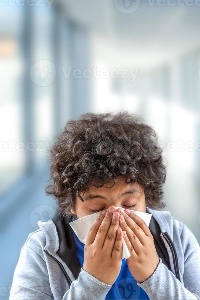 young teenager cold flu illness tissue blowing runny nose.- Kid blowing his nose. Seasonal virus caught photo