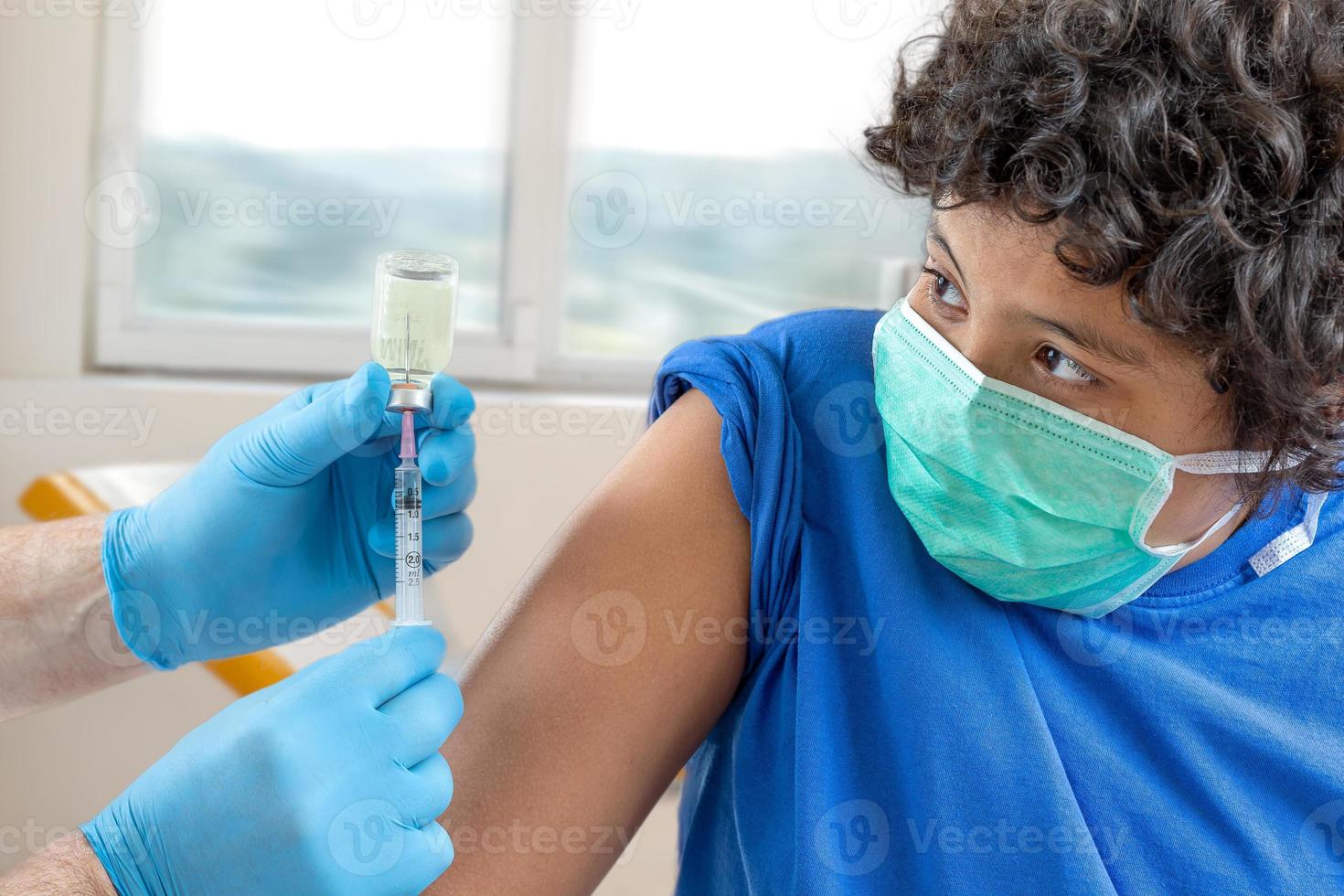 médico varón con mascarilla protectora guantes de látex que administran vacunación intramuscular brazo protegido del paciente foto