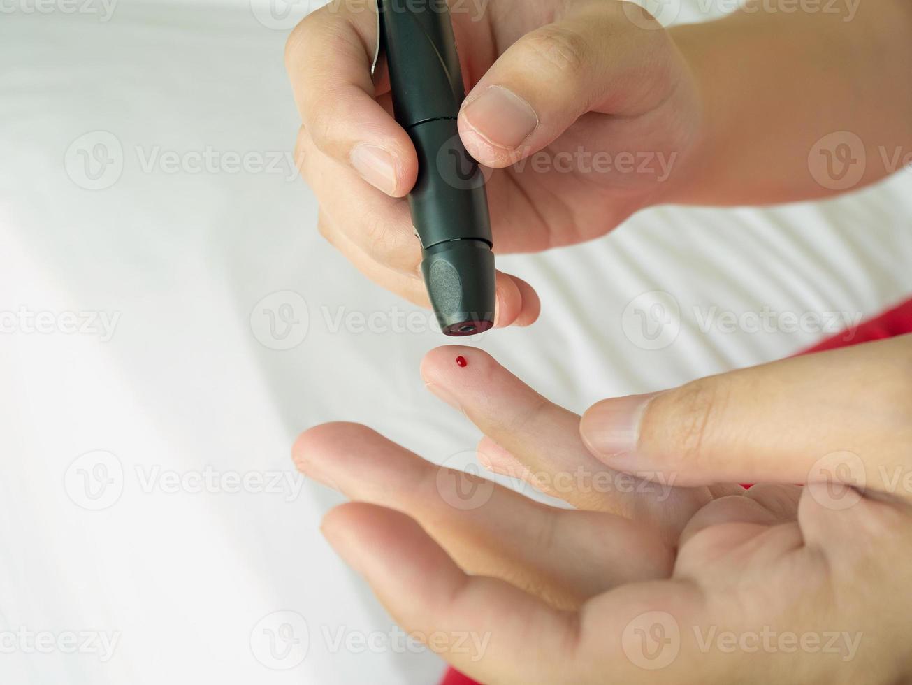 woman using lancelet on finger, diabetes test photo