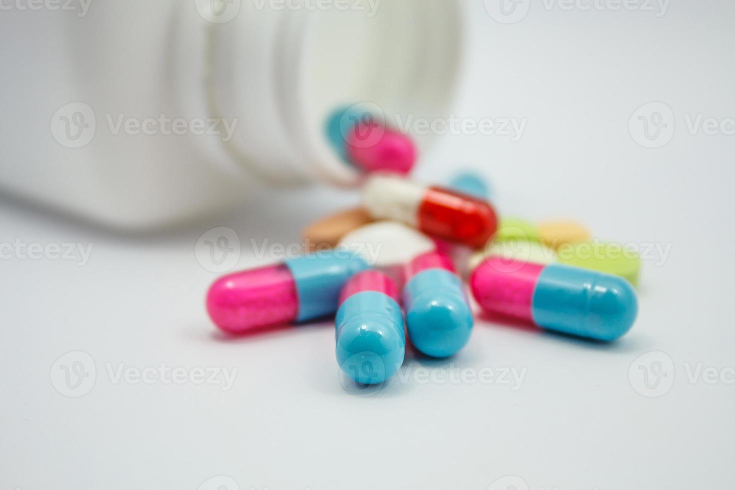 Colored pills, tablets and capsules on white background photo