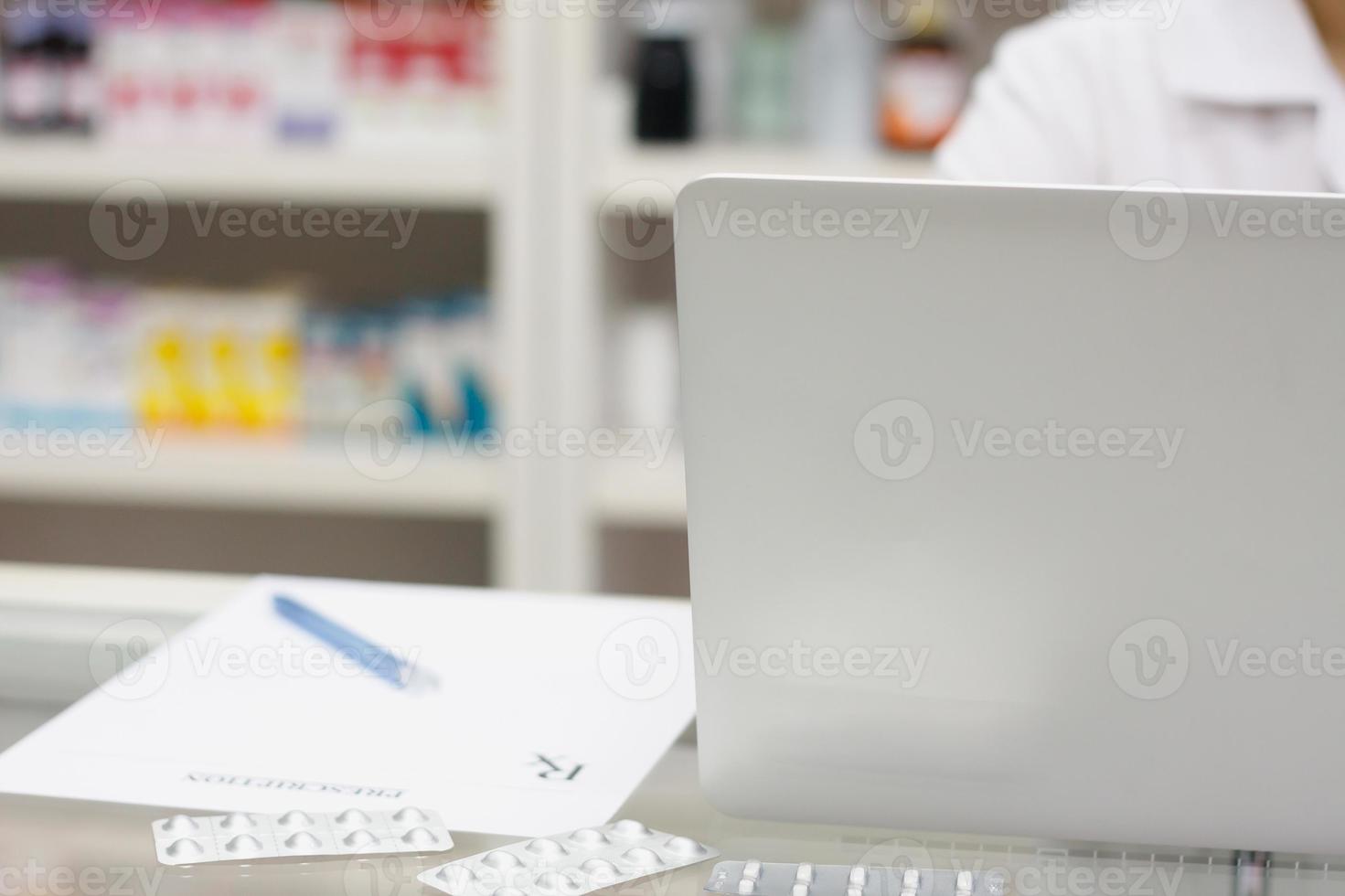 Pharmacist with laptop computer and medication in the pharmacy photo