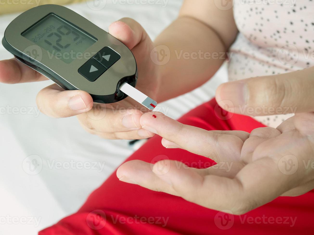 measuring glucose level with digital glucose meter photo