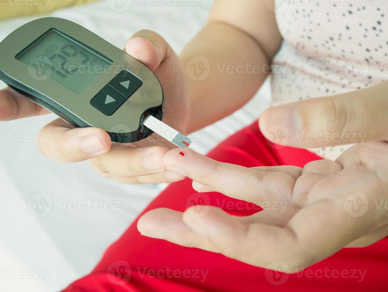 measuring glucose level with digital glucose meter photo