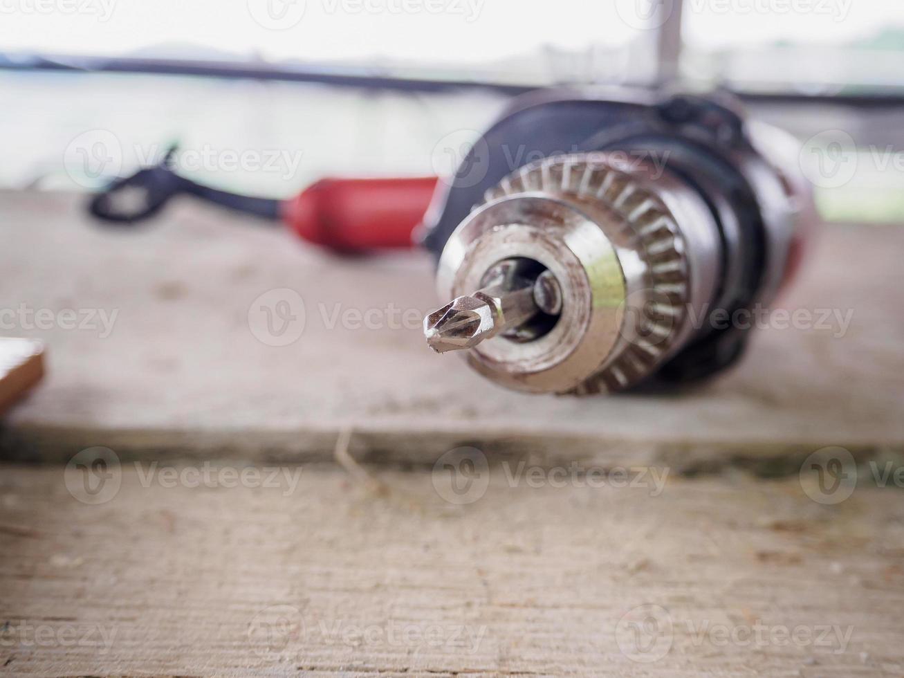 cierre un taladro eléctrico en el lugar de trabajo sobre una tabla de madera foto