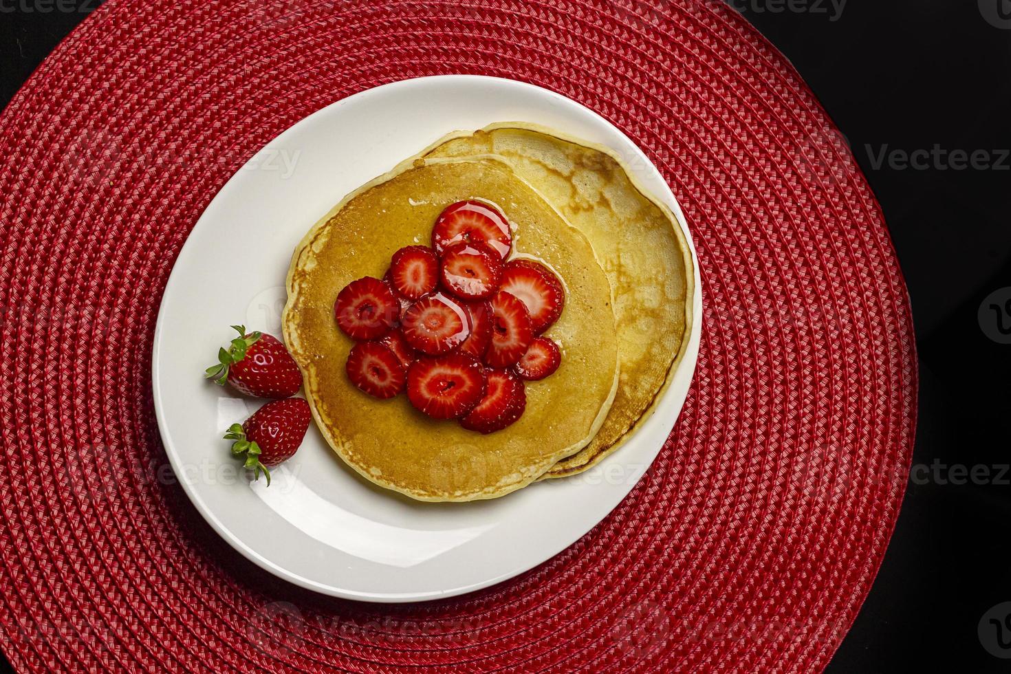 Topview of delicious pancake with strawberries and syrup. photo