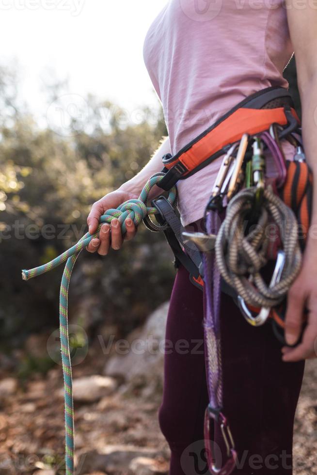 A rock climber prepares equipment for climbing, woman holds a rope, knot photo