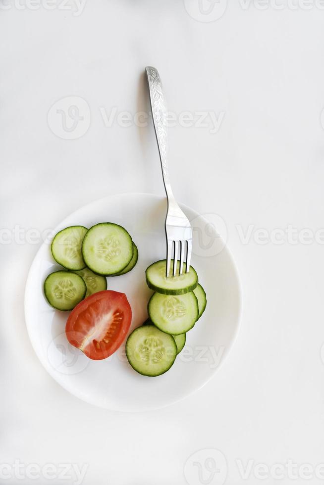 pepino en rodajas en un plato blanco y tomates foto