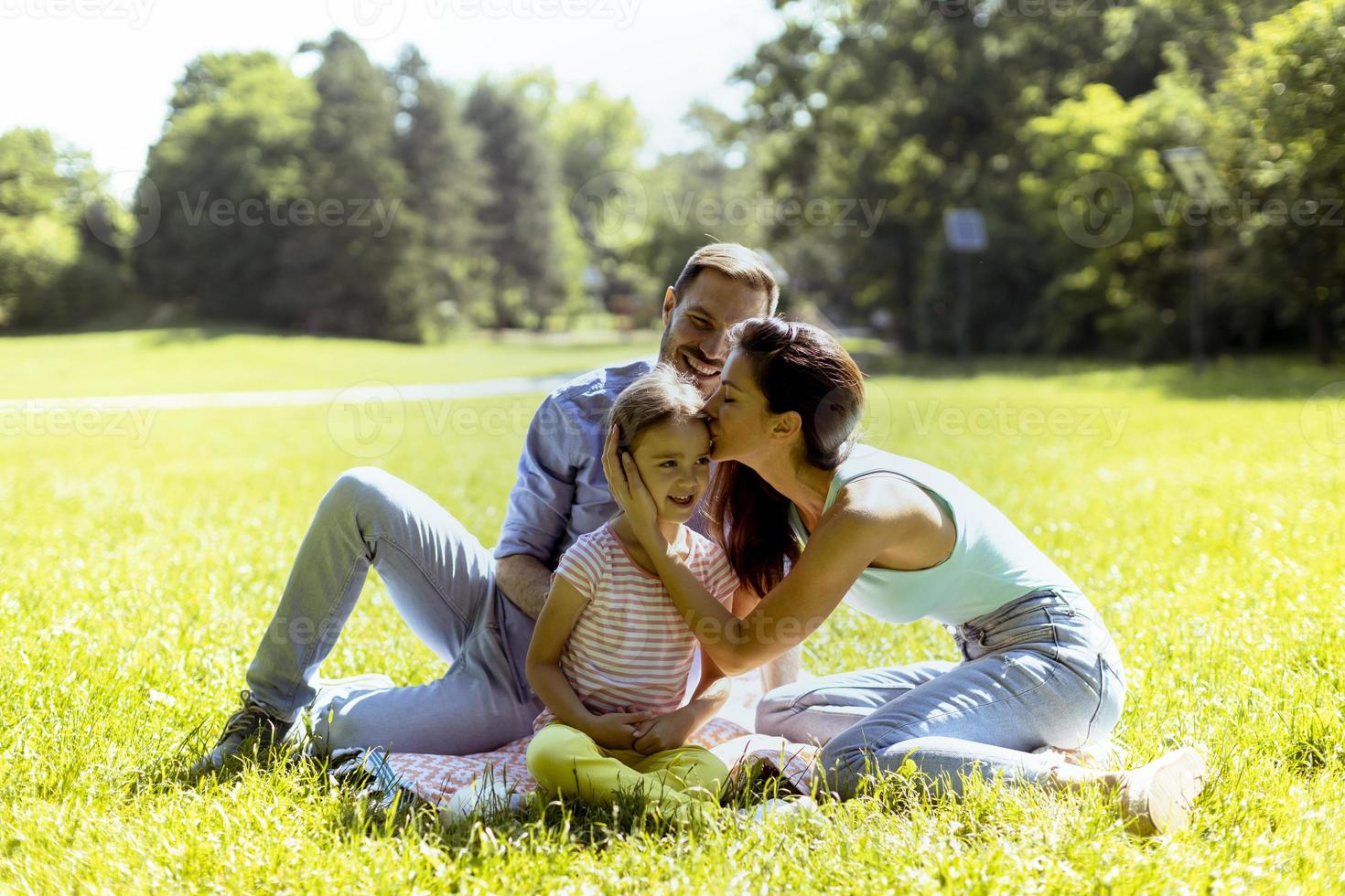 Happy young family with cute little daughter having fun in the park on a sunny day photo
