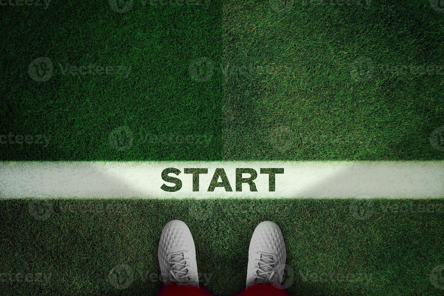 Top view of white soccer boots on green field whith text START. photo