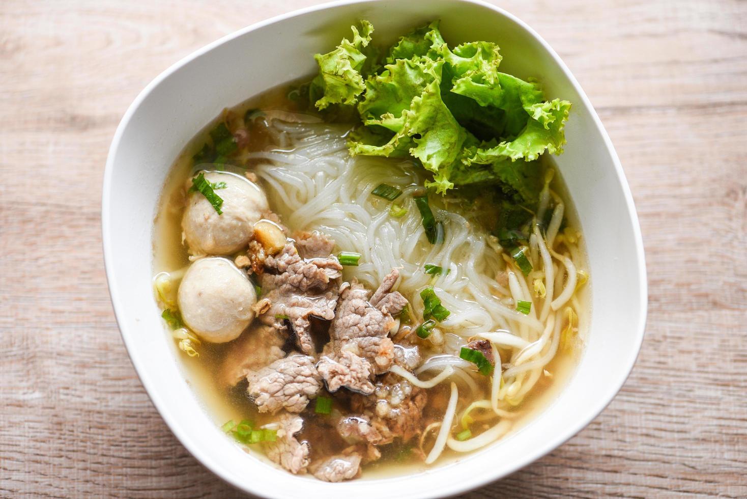 Noodle soup bowl fresh vegetable lettuce pork and Pork balls on wooden background, Thai traditional menu food photo