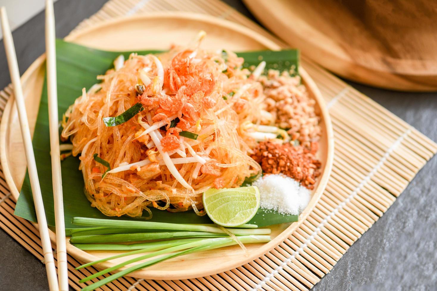 Thai food fried noodle Thai style with prawns bean sprout and garnish peanuts chili powder sugar lemon lime, Stir-fry noodle Pad Thai on plate served on the dining table food photo