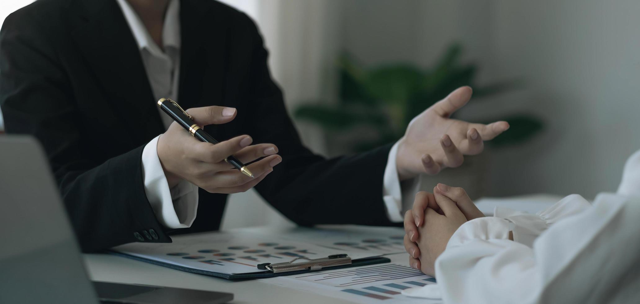 Team businesswoman explaining the structure of the business and another employee listens discreetly. along with the documents on the desk and laptop in the office photo