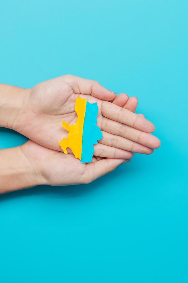 Support for Ukraine in the war with Russia, Hands holding the shape of Ukraine border with color flag. Pray, No war, stop war and stand with Ukraine photo