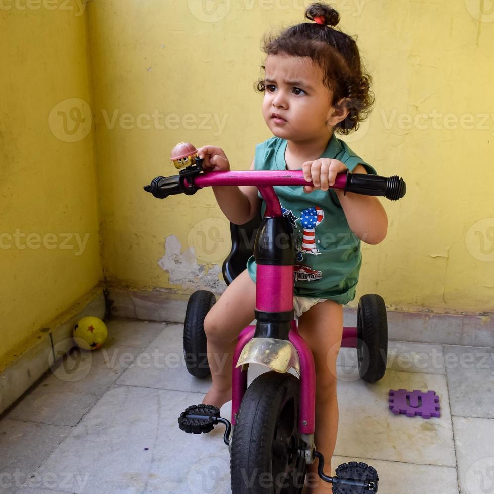 lindo niño pequeño shivaay conduciendo en bicicleta en el balcón de la casa durante el verano, dulce sesión de fotos de niño pequeño durante el día, niño pequeño disfruta de andar en bicicleta en casa durante la sesión de fotos