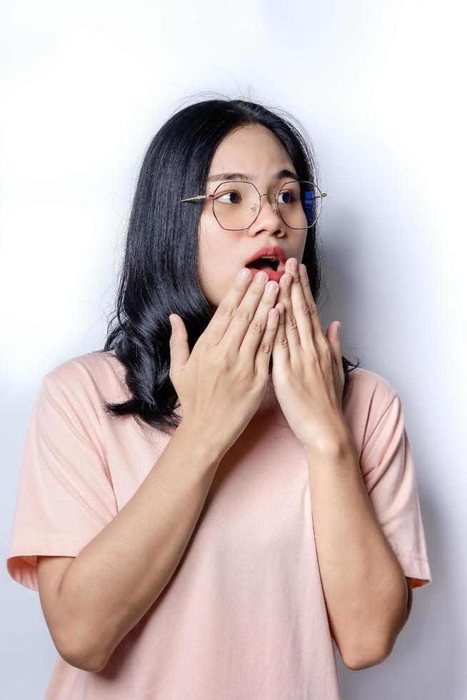 Surprised beautiful woman holding her cheeks by hand in amazement and open-mouthed. Happy young female model looks at camera as notices something unexpected hears good news. photo