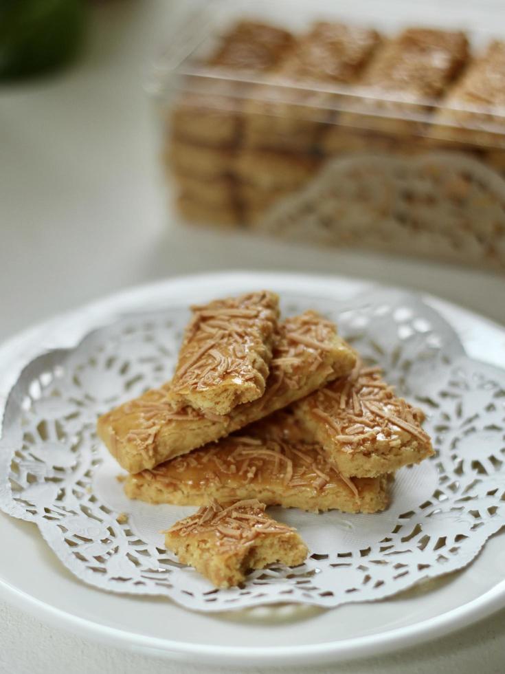 High angle view of Indonesian cheese sticks called kaastengel, on white rustic paper, with blurred background and uneven white color table. photo