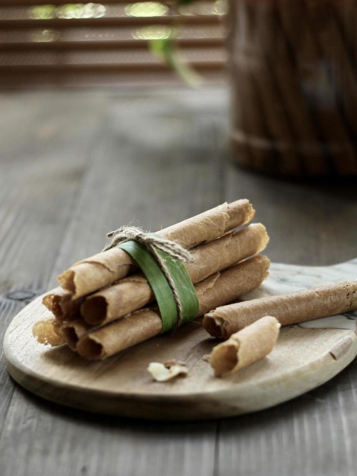 High angle view of Indonesian crispy egg roll on wooden cutting board with blurred bamboo window at the back. photo