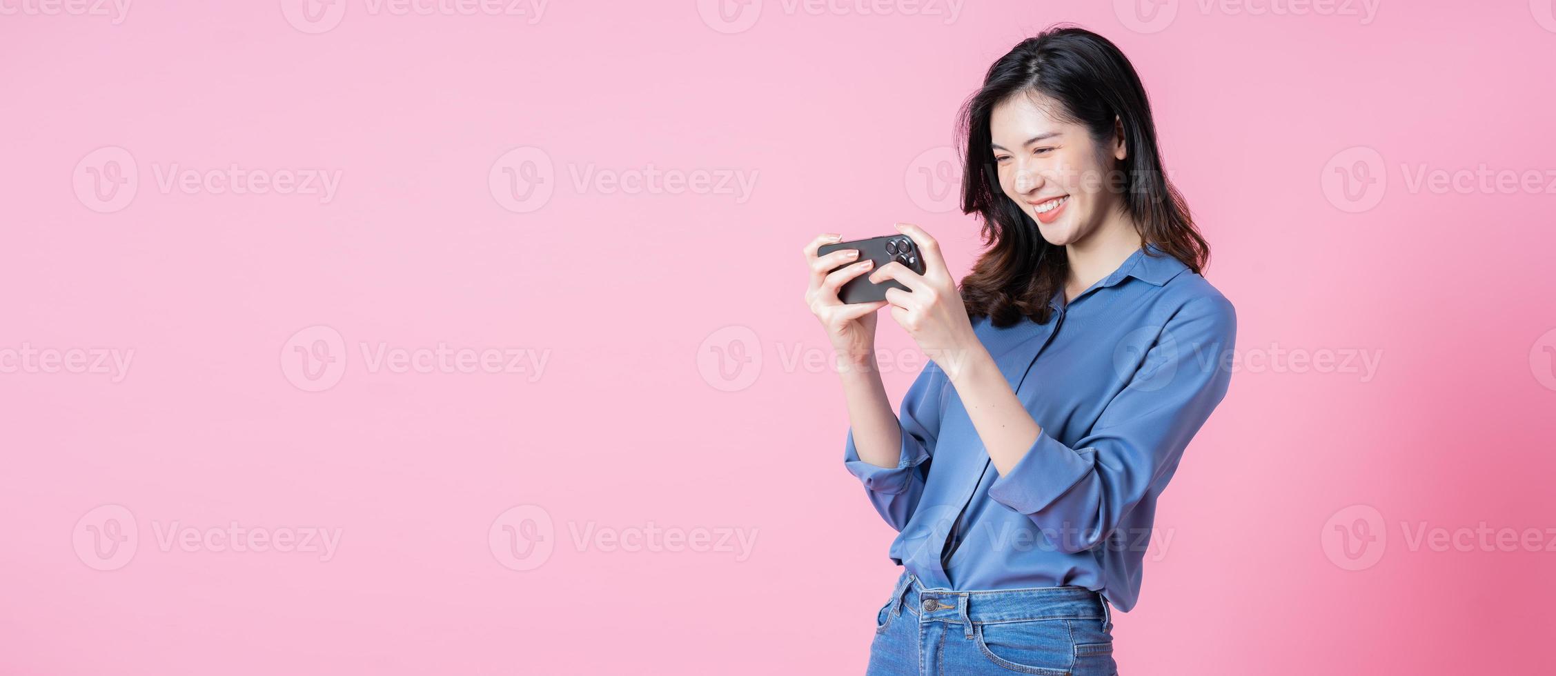 Image of young Asian business woman using smartphone on pink background photo