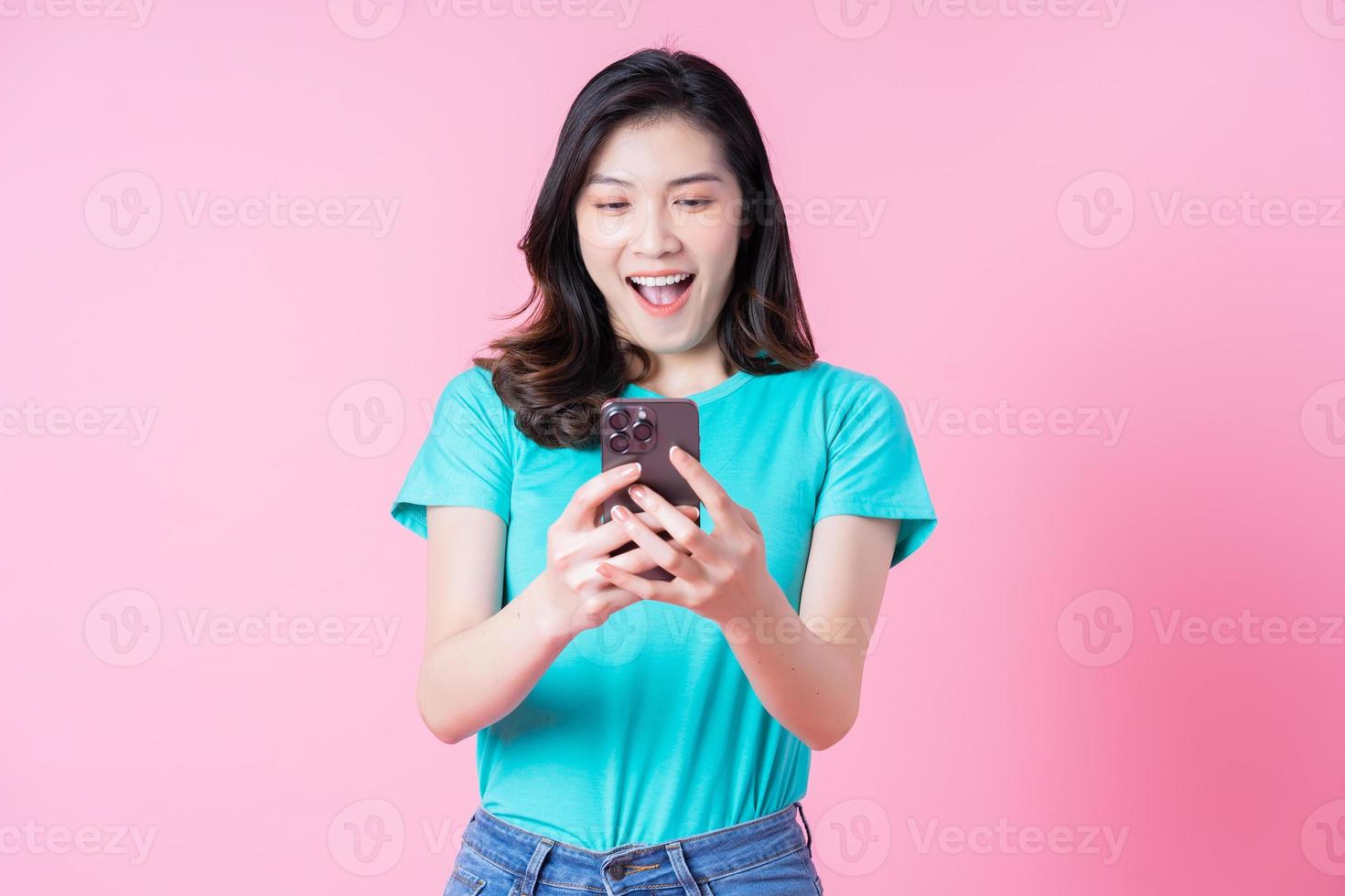 Joven mujer asiática con smartphone sobre fondo rosa foto