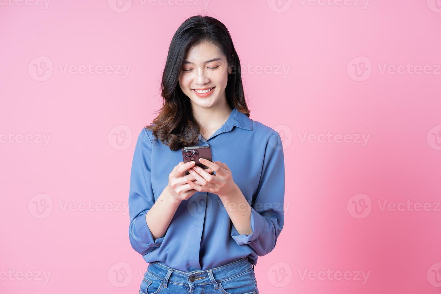 Image of young Asian business woman using smartphone on pink background photo