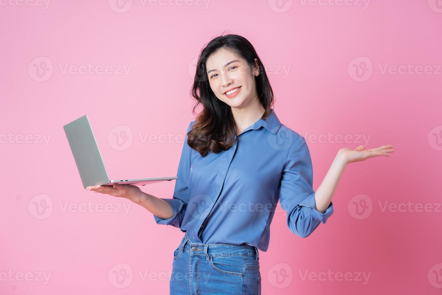 Young Asian businesswoman using laptop on pink background photo