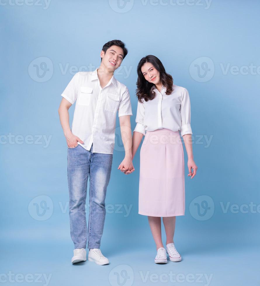 Full length image of young Asian couple on blue background photo