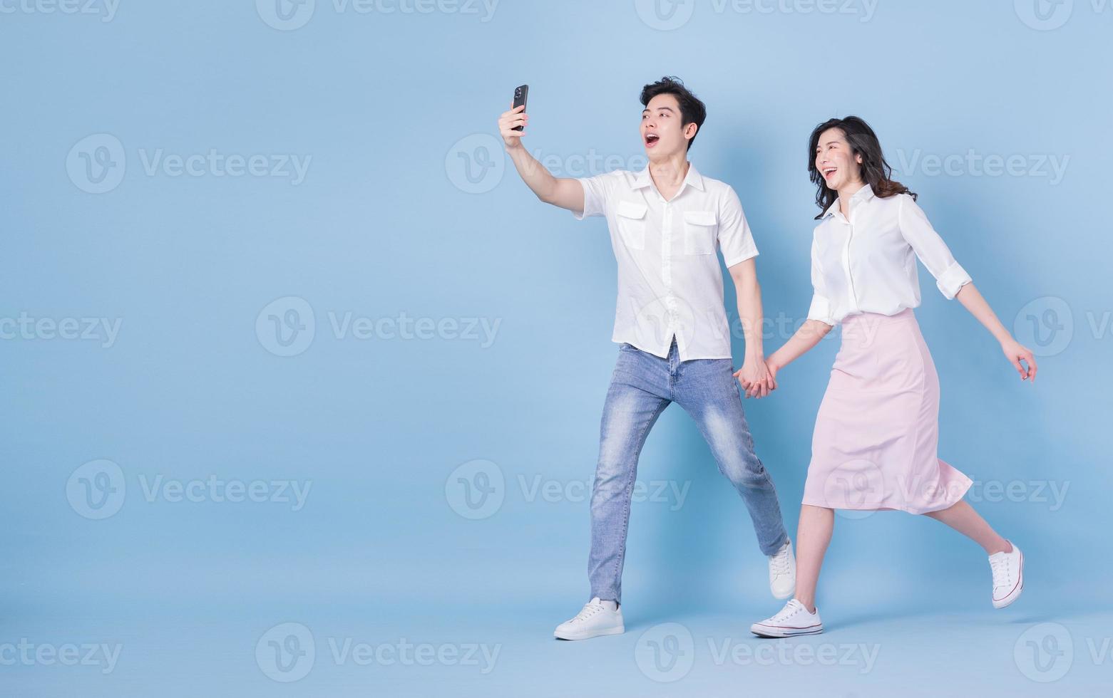 Full length image of young Asian couple on blue background photo