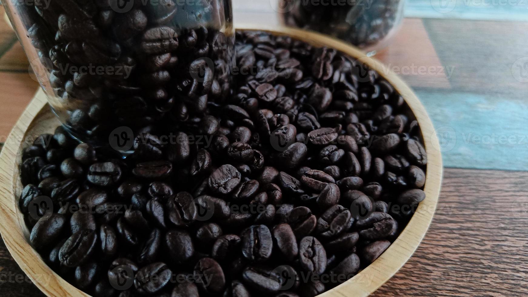 Close-up view of coffee beans and a glass bottle on a wooden plate photo