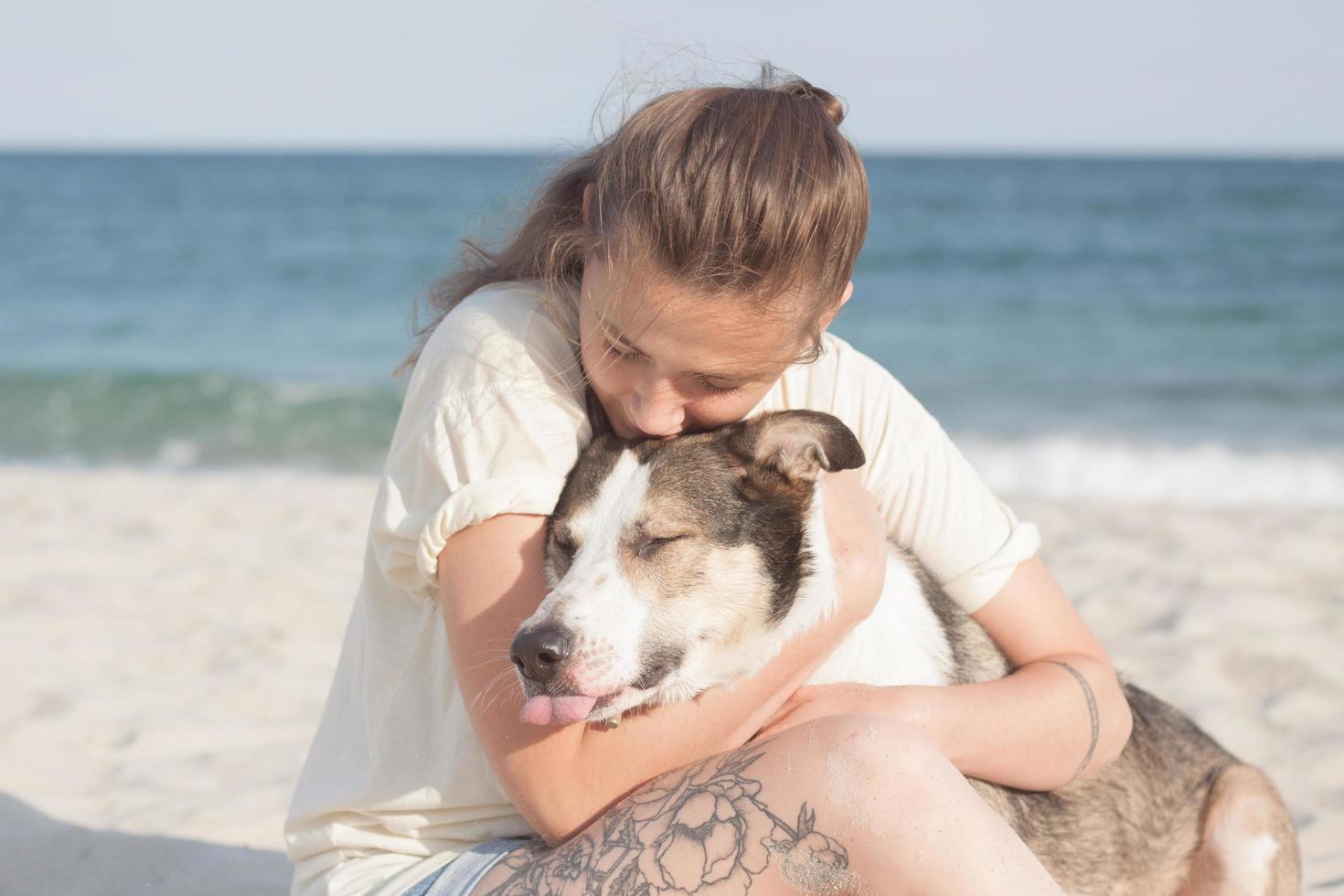 mujer juega con perro en la playa foto