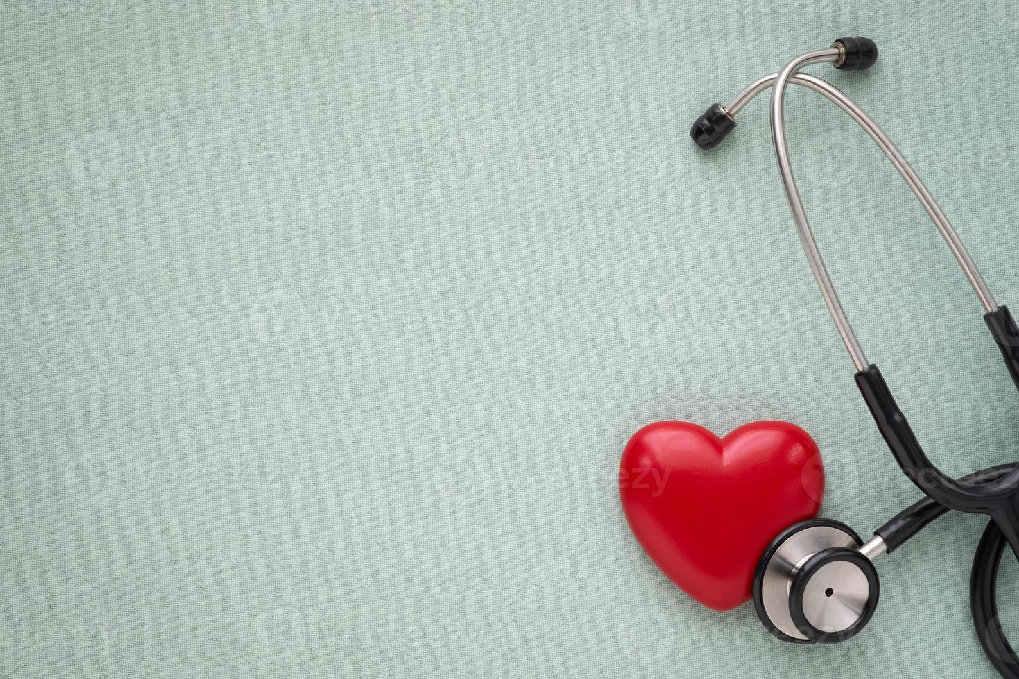 Black stethoscope with red heart of doctor for check up on light green background. Stethoscope equipment of medical use to diagnose hear sound. Health care and cardiology concept with copy. photo