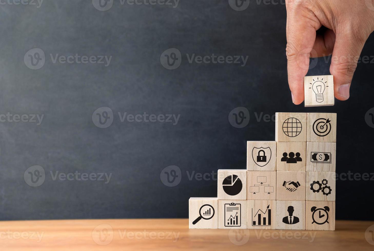 Hand arranging wood blocks stacking with business icon on wooden table background. Business investment and finance accounting concept for growth success process with copy space. photo