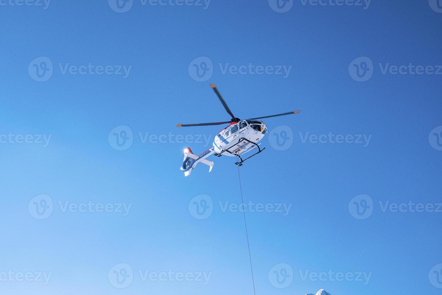 Police helicopter flying above against blue sky on sunny day photo