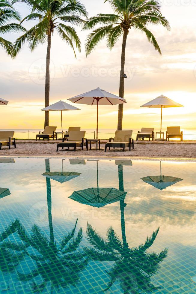 Umbrella and chair around swimming pool in hotel resort with sunrise in morning photo