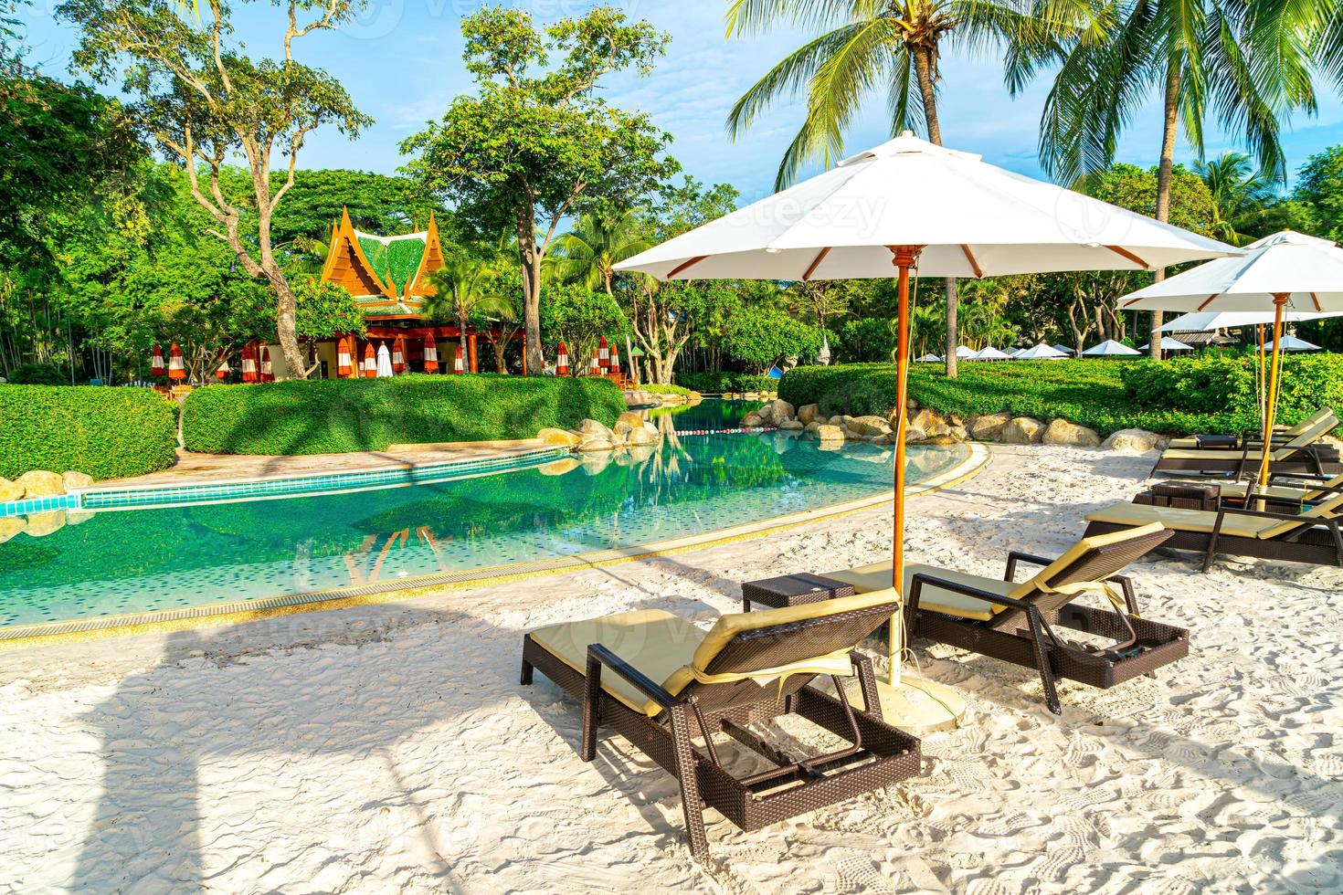 Beautiful luxury umbrella and chair around outdoor swimming pool in hotel and resort with coconut palm tree on sunset  or sunrise sky photo