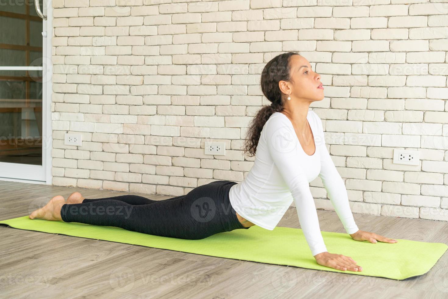 Latin woman practicing yoga on mat photo