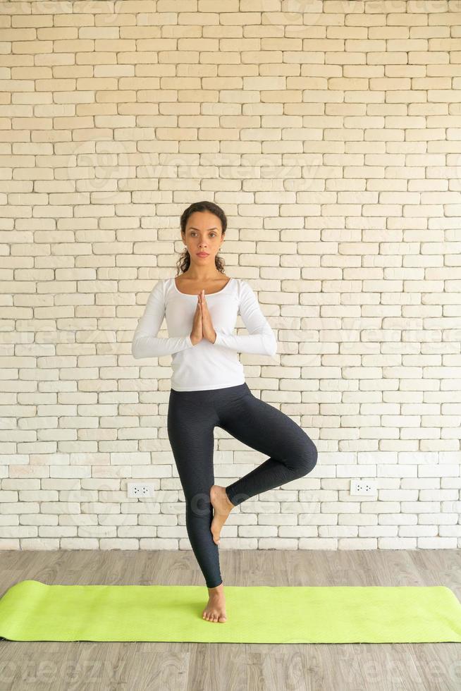 Latin woman practicing yoga on mat photo