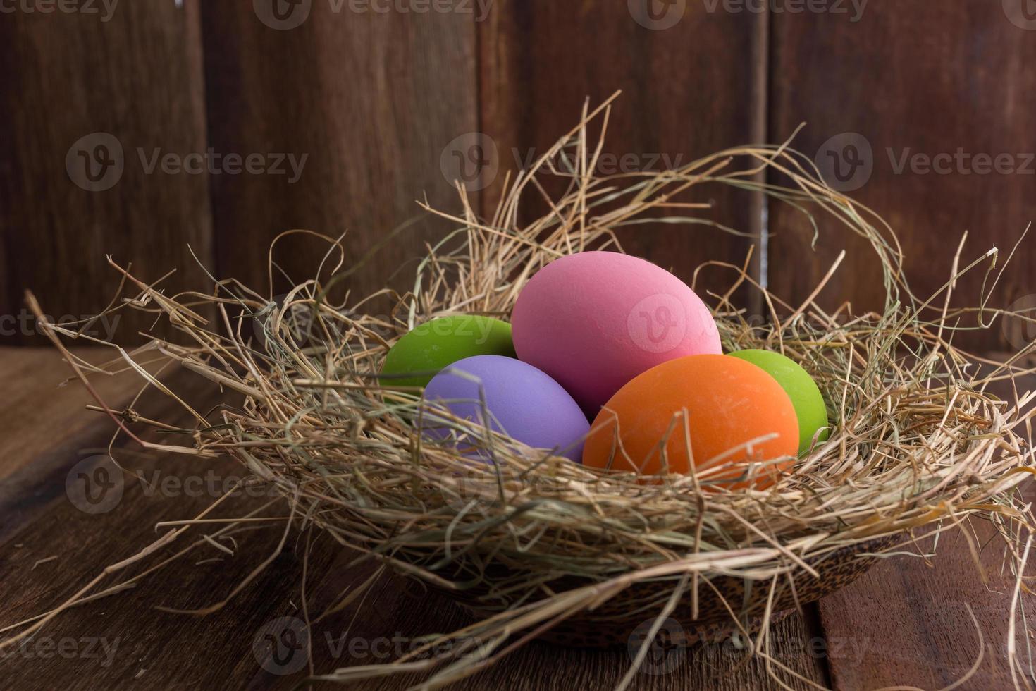 Easter eggs in nest on old wooden background photo