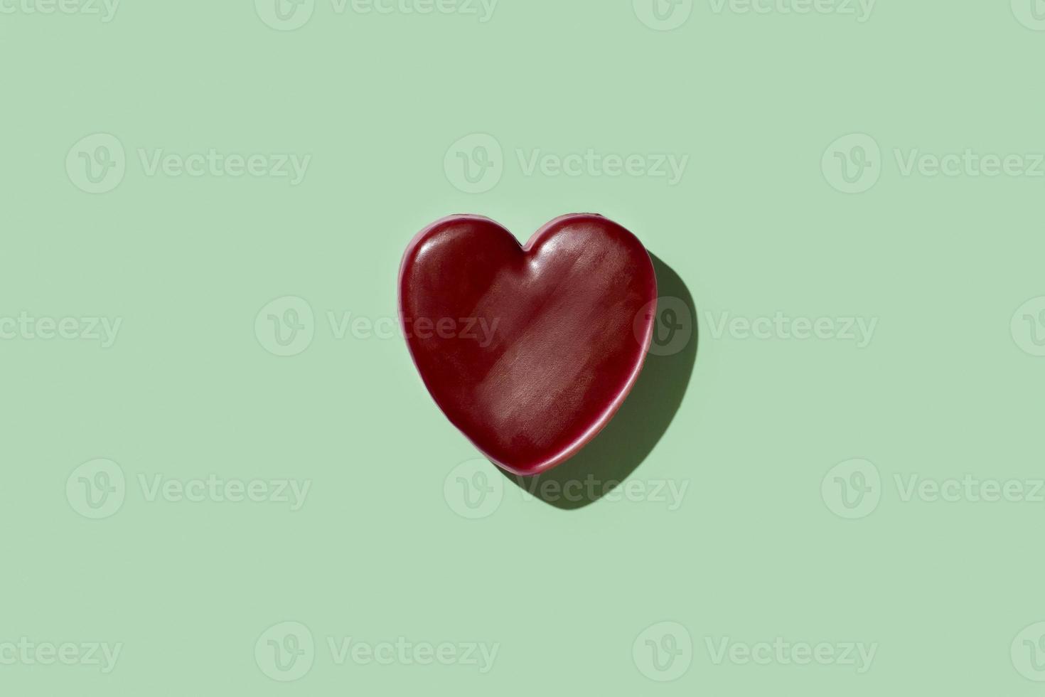 Red wax heart on green background photo