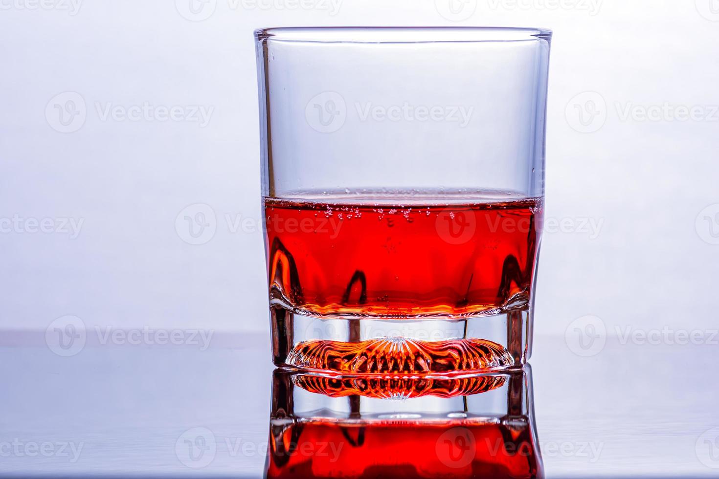 Glass of whiskey and ice on a glass table photo