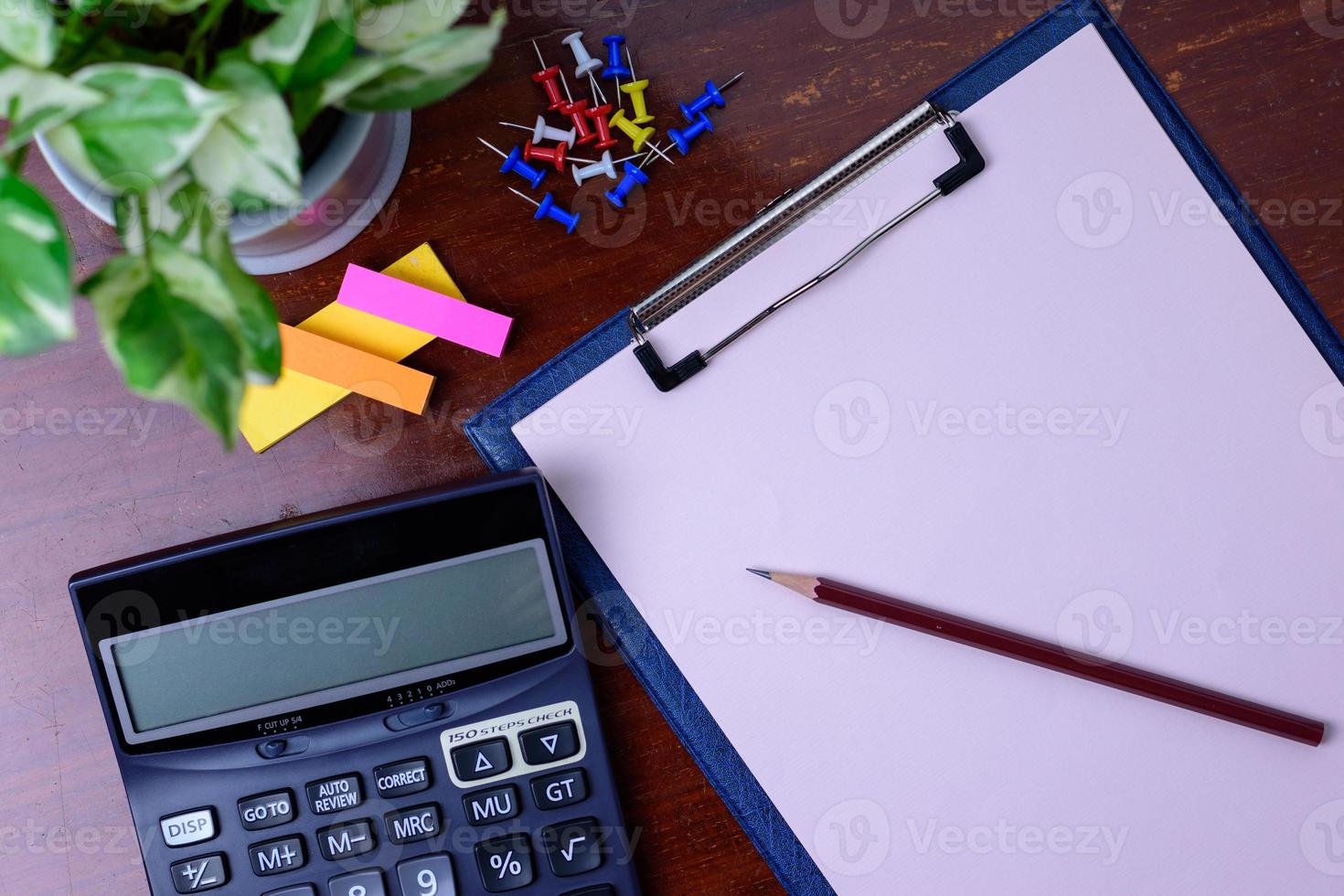 Calculator, file, pencil and office supplies. Placed beside a tree on a wooden table. photo