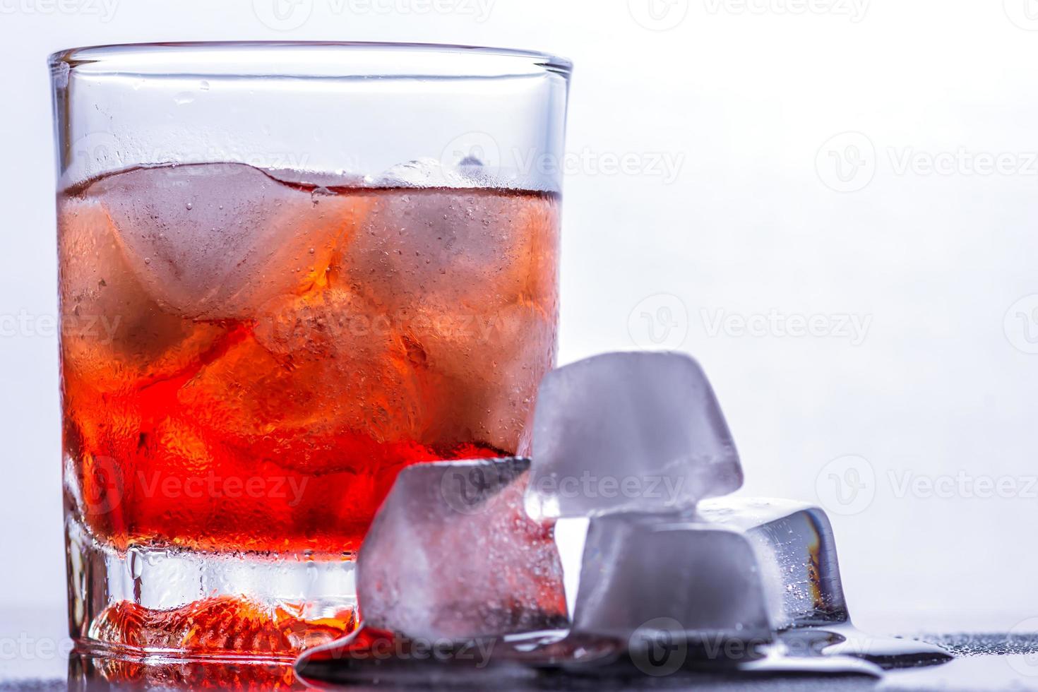 Glass of whiskey and ice on a glass table photo