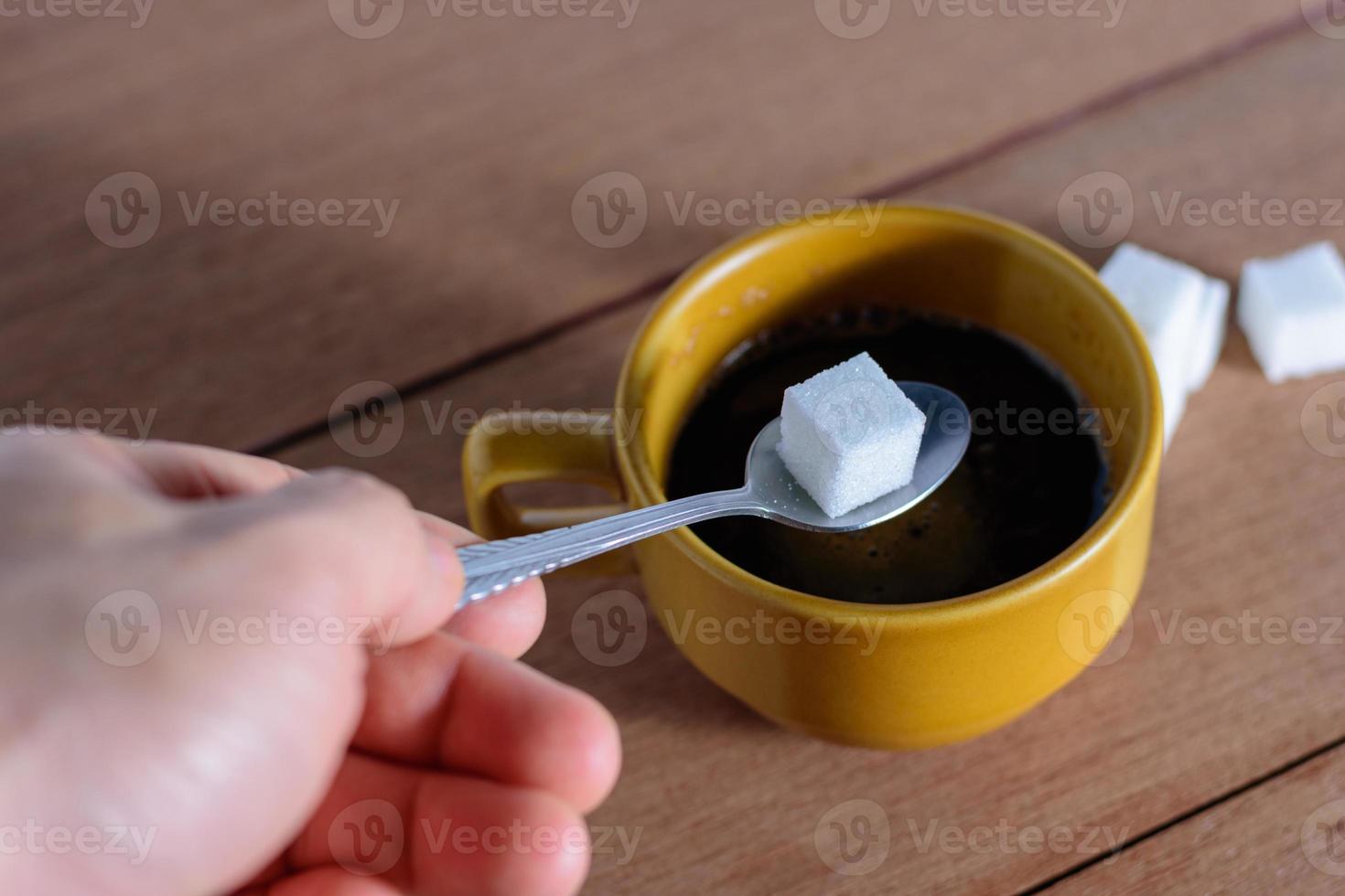 The hand is filling the sugar into the coffee. photo