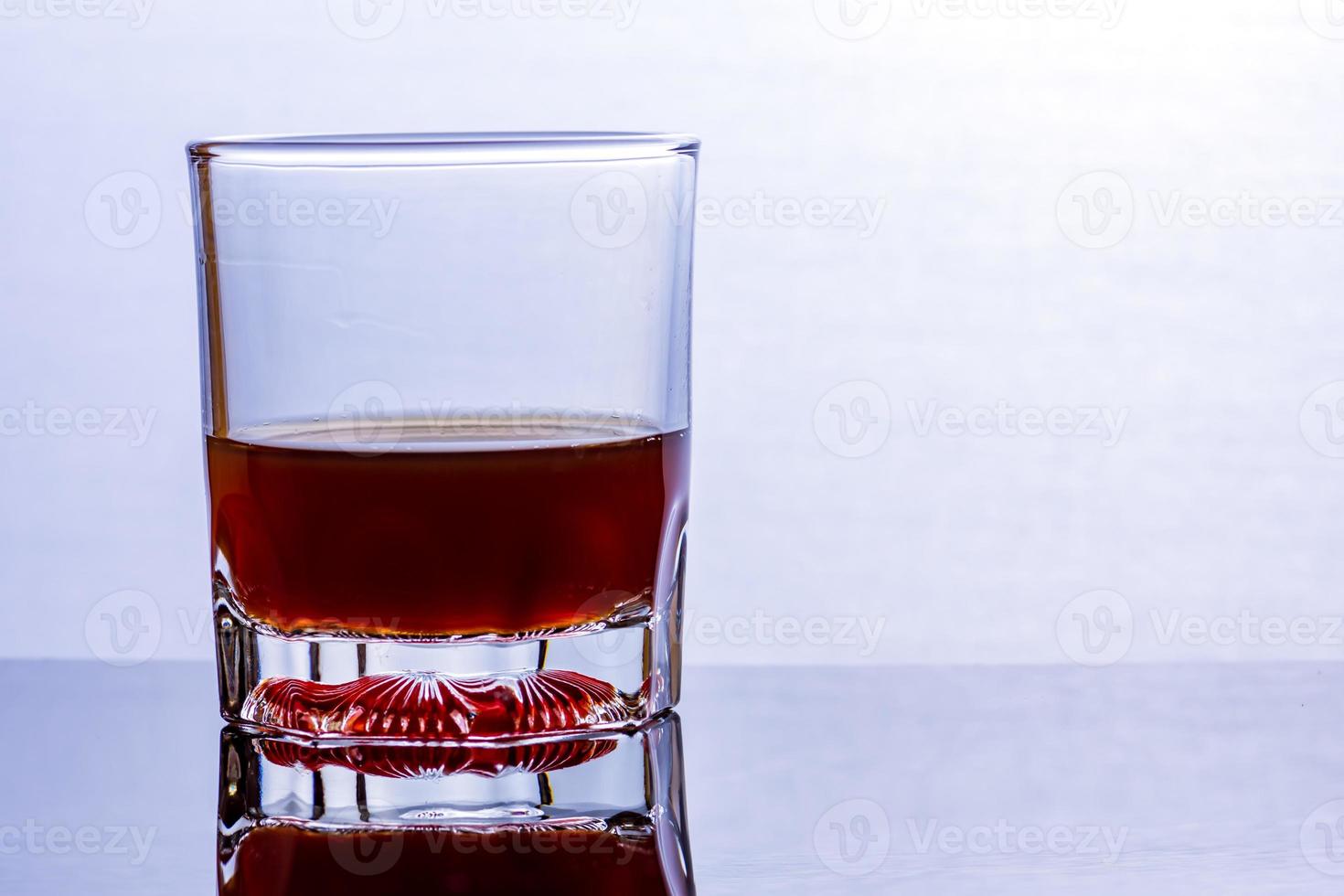 Glass of whiskey on a glass table photo