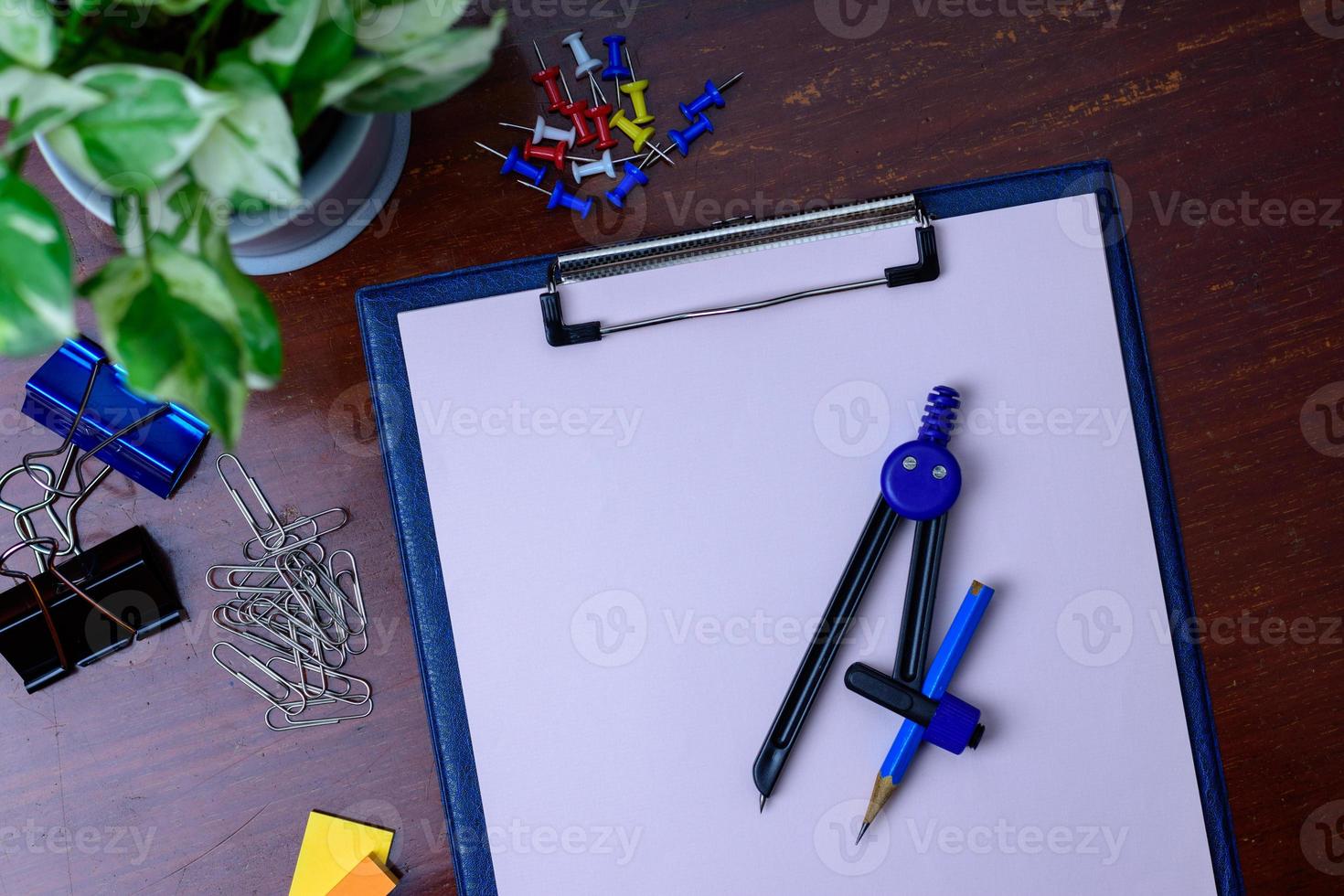 archivo, lápiz y material de oficina. colocado al lado de un árbol en una mesa de madera. foto