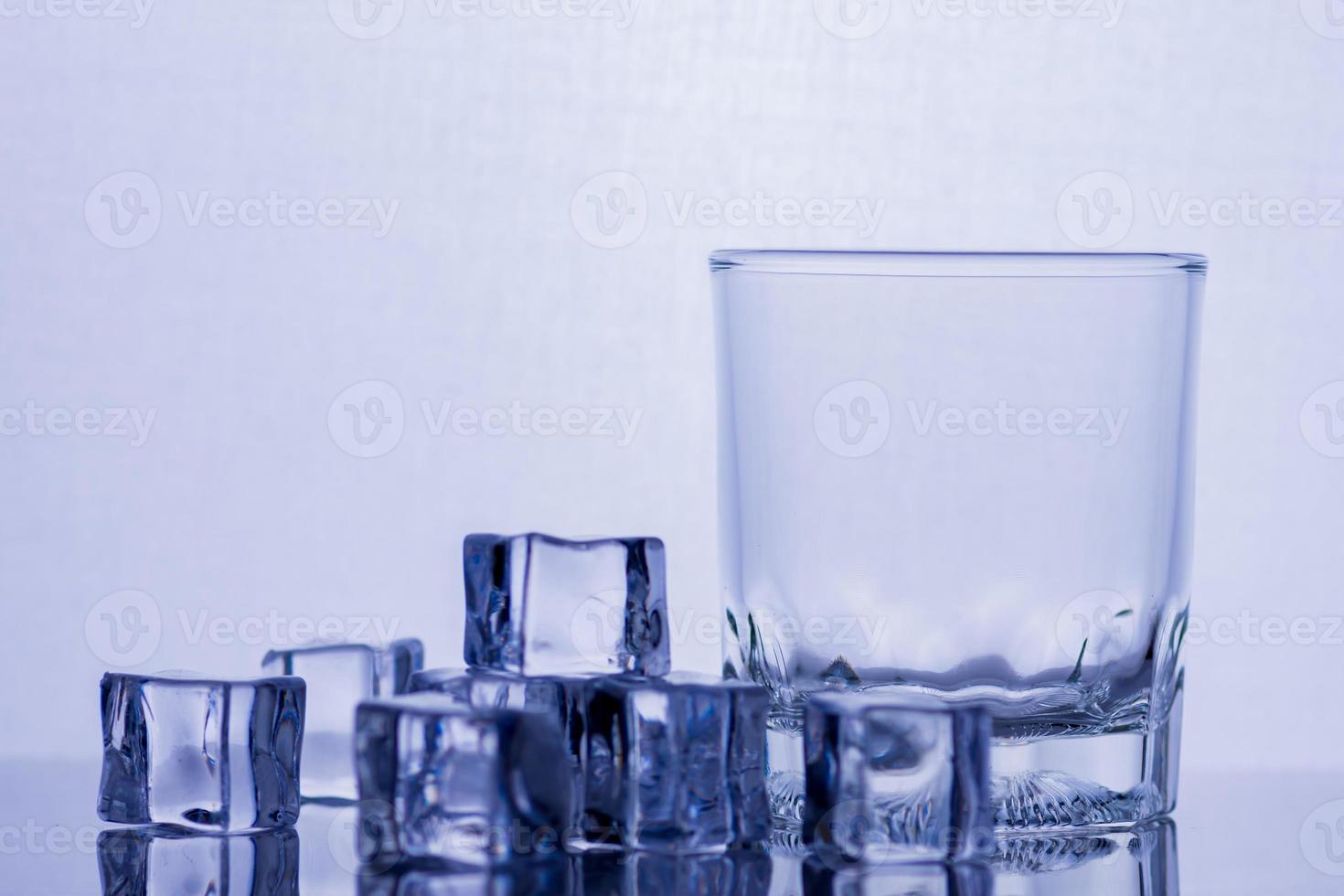 Glass of whiskey and ice on a glass table photo