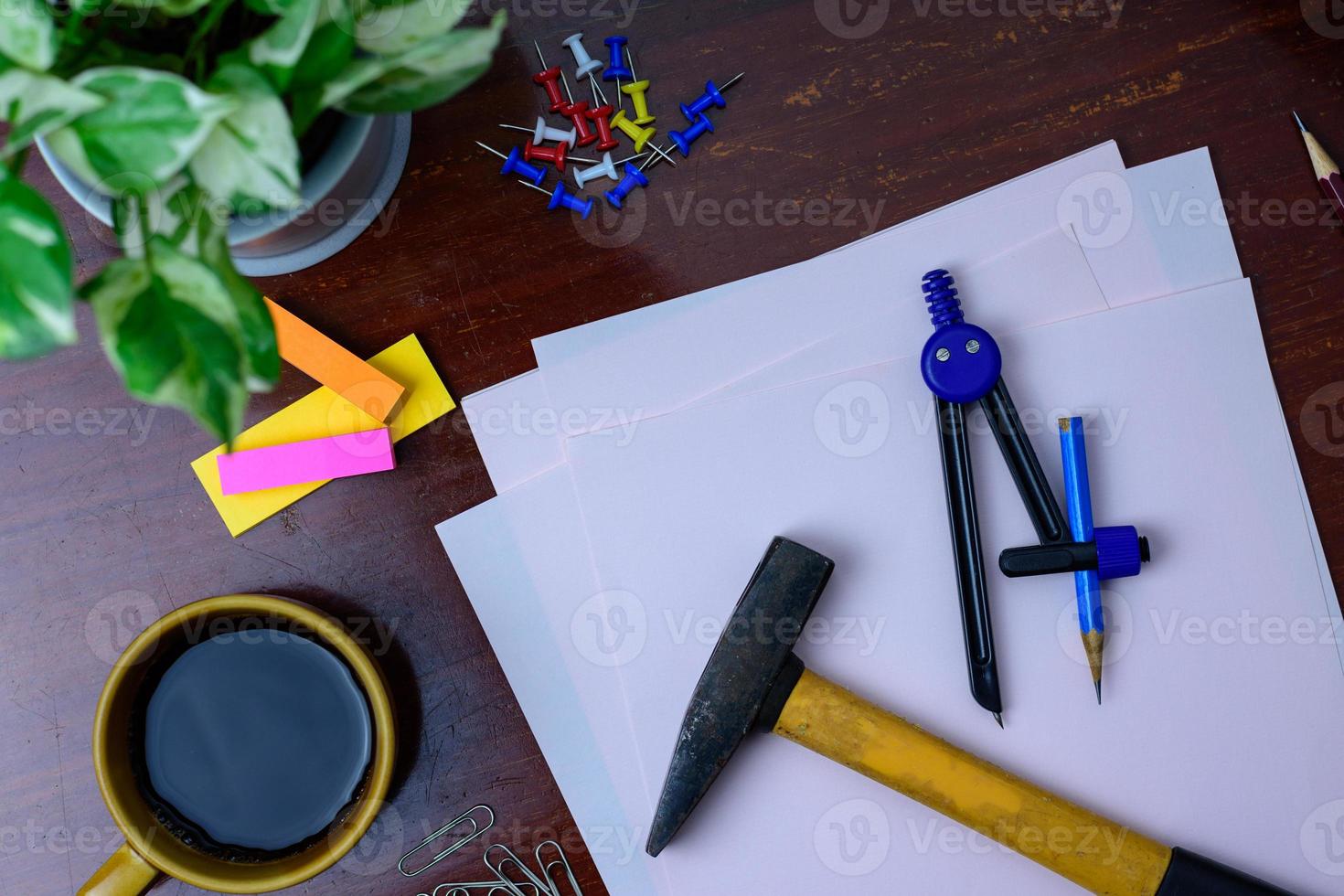 Coffee, hammer, file, pencil and office supplies. Placed beside a tree on a wooden table. photo