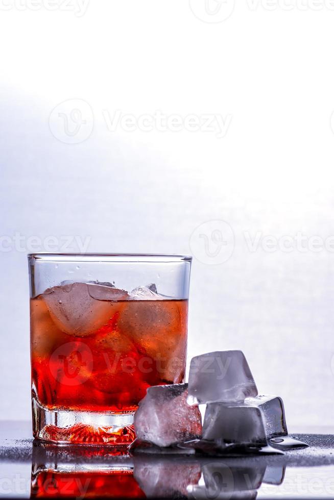 Glass of whiskey and ice on a glass table photo