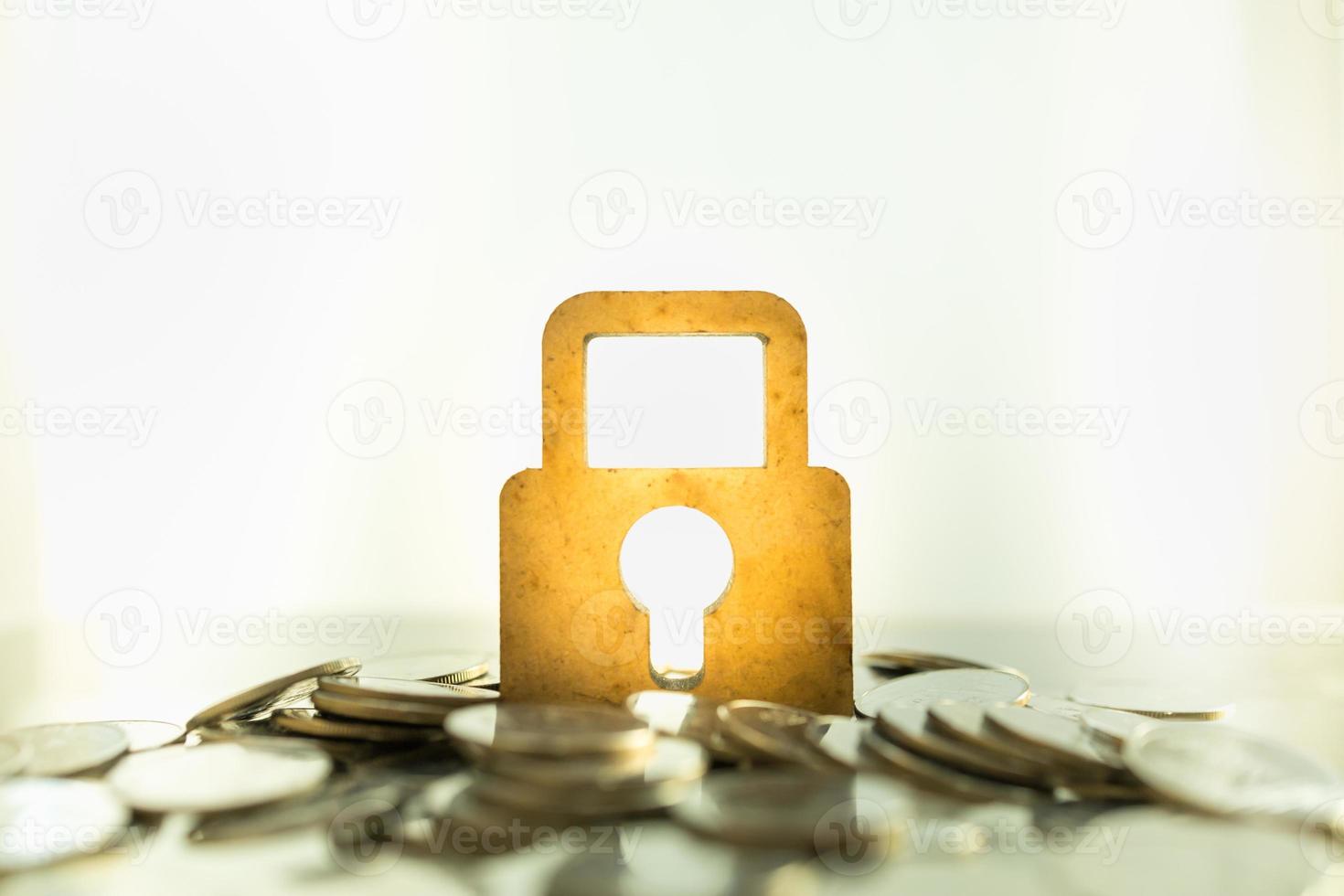 Money and Security Concept. Close up of wooden master key lock icon on pile of coins with copy space. photo