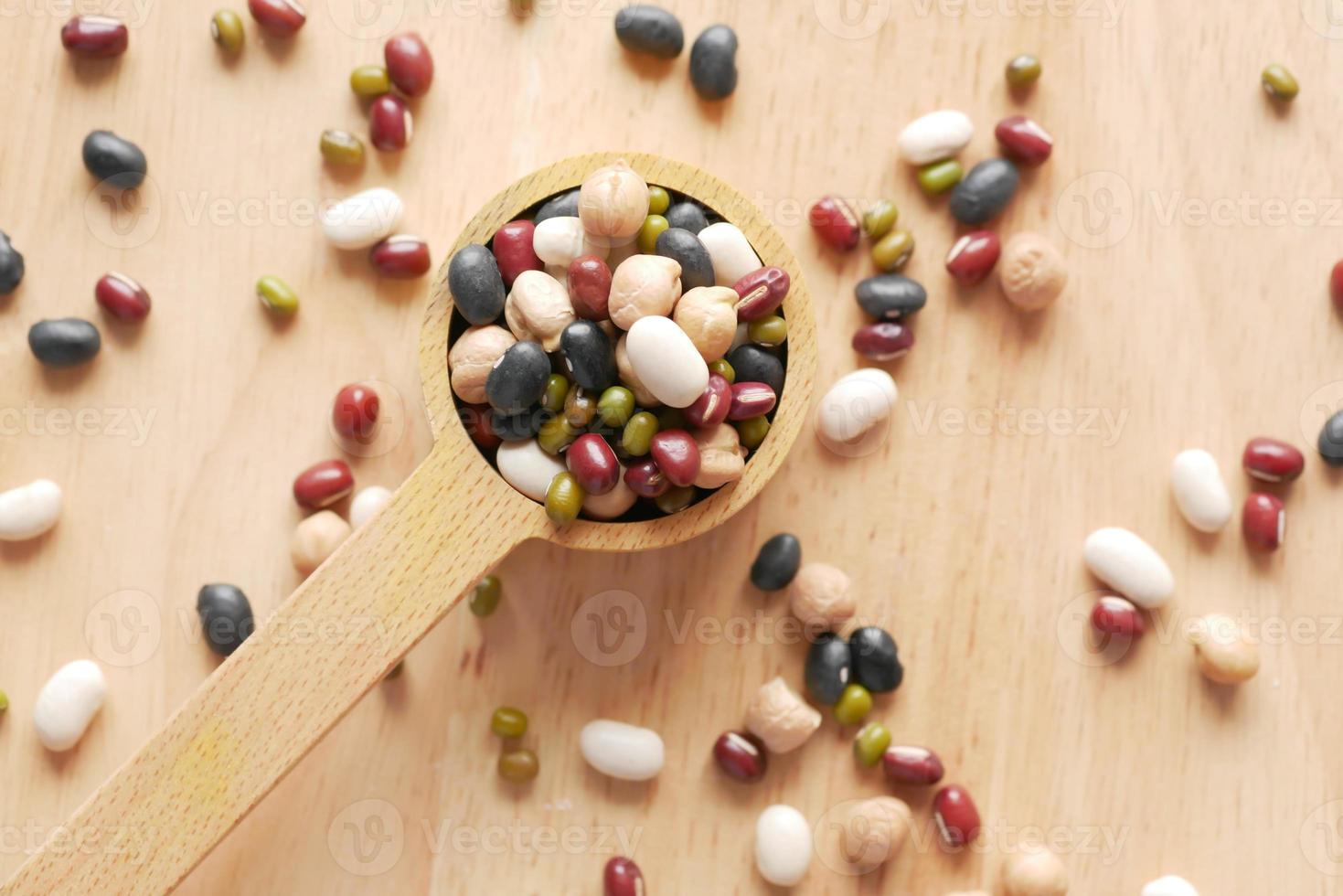 close up of mixed beans in a wooden spoon on table photo