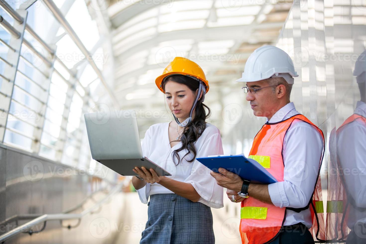 el ingeniero y la mujer de negocios revisando el portapapeles en el edificio del sitio de construcción. el concepto de ingeniería, construcción, vida urbana y futuro. foto